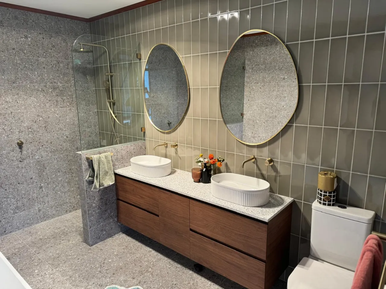 Bathroom with a double vanity, two round mirrors, gold-finish wall taps and a walk-in shower